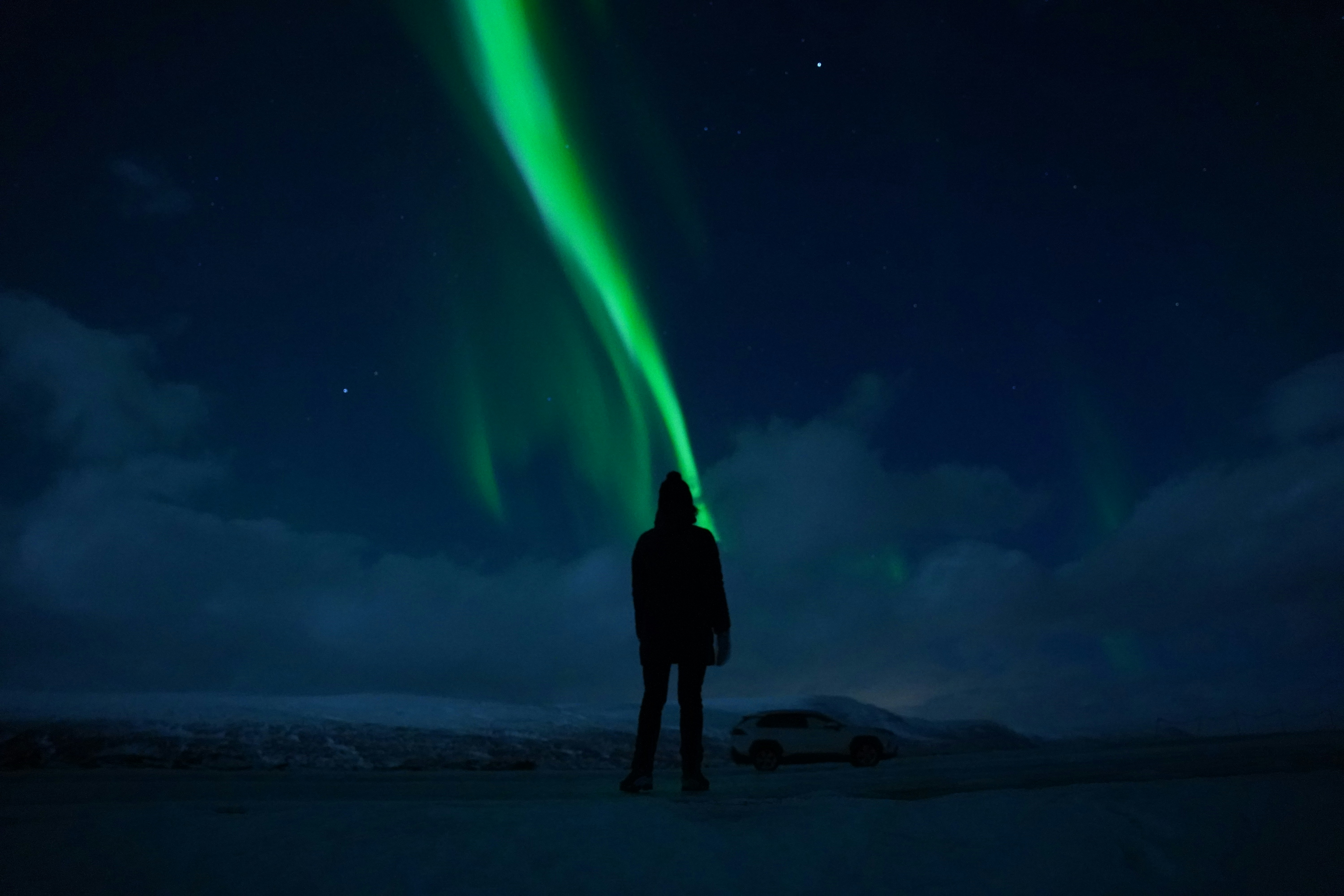 Silhouette d'un homme de dos regardant une aurore boréale